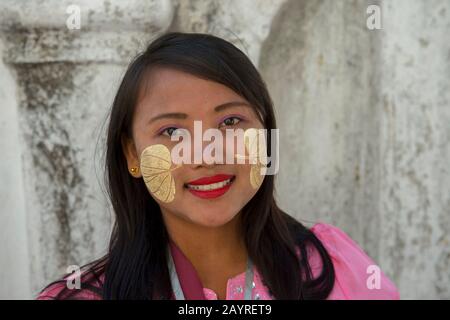 Ritratto di una giovane donna con una pasta decorativa fatta dall'albero Thanaka sul suo viso alla Pagoda di Kutodaw sulla collina di Mandalay, Mandalay, Myanmar Foto Stock