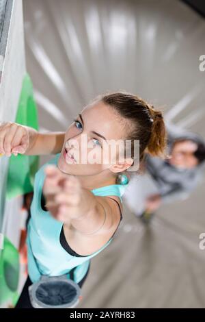 aiutando un bel climber sorridente femmina a raggiungere una cima Foto Stock