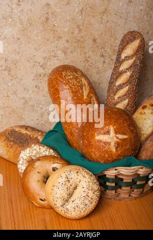 Varietà di pane fatto in casa, con alcuni in un cesto di vimini con un tovagliolo di stoffa, tra cui ciotola di pane con pasta di lievito, pane con pasta di sourdough, tre pagnotta di semi, tre c. Foto Stock