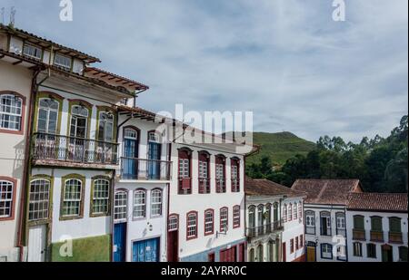 Bellissimo paesaggio di case colorate in stile coloniale con influenza barocca portoghese e montagna sullo sfondo in Ouro Preto, Brasile. Pre Ouro Foto Stock