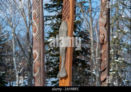 Pali in legno intagliato Ainu di fronte al centro di spettacolo Ainu in Ainu Kotan, che è un piccolo villaggio Ainu in Akankohan nel Parco Nazionale di Akan, Hokk Foto Stock