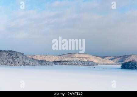 Vista del lago ghiacciato Abashiriko e della foresta coperta di neve vicino Abashiri, una città sull'Isola di Hokkaido, Giappone, con tende colorate allestite sul ghiaccio per Foto Stock