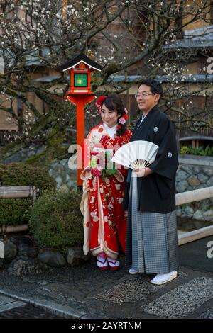 Una coppia di nozze si posa ad una lampada al canale di Shirakawa nel quartiere di Gion a Kyoto, Giappone. Foto Stock