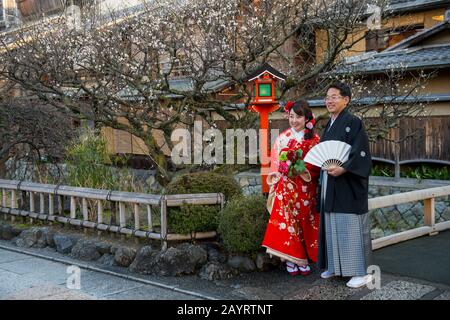 Una coppia di nozze si posa ad una lampada al canale di Shirakawa nel quartiere di Gion a Kyoto, Giappone. Foto Stock