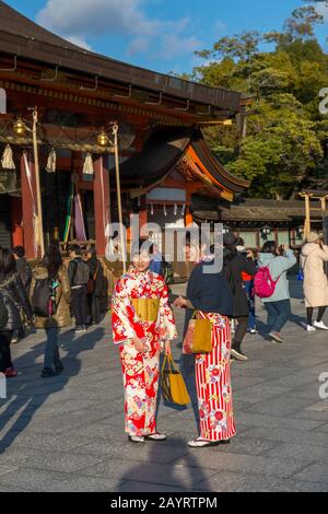 Giovani donne vestite con kimono che posano davanti al Santuario Yasaka, che è un santuario shintoista nel Distretto Gion di Kyoto, Giappone. Foto Stock