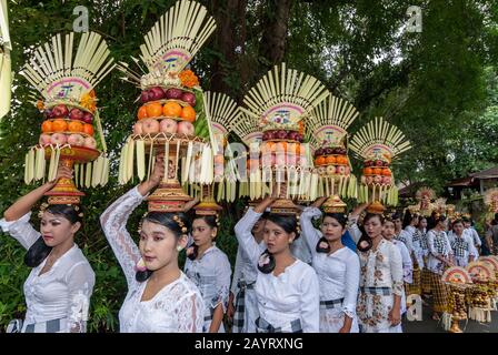 Bali, Indonesia - 26 luglio 2010: Gruppo di donne in costumi tradizionali e colorata offerta sulle loro teste a piedi al tempio sacro pura Tanah Lot. Foto Stock