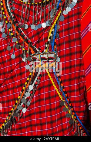 Primo piano del vestito tradizionale e gioielli in vetro di un giovane guerriero Maasai in un villaggio Maasai nel Masai Mara in Kenya. Foto Stock