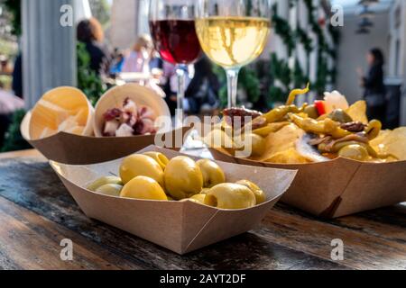 Tapas bar. Olive, patatine fritte, formaggio e jamon, vino rosso e bianco, su un tavolo di legno in un caffè all'aperto Foto Stock