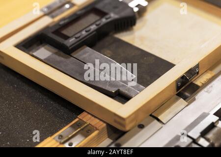 La pinza elettronica è posta in una scatola di legno, strumento di controllo della qualità di produzione Foto Stock