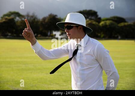 Cricket umpire facendo segni in piedi su un campo di cricket Foto Stock