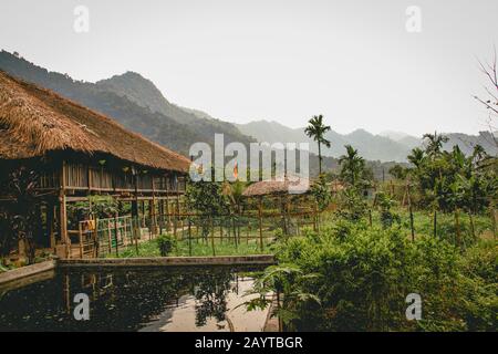 Una casa nativa indigena degli hmong con le montagne carsiche nebbiose sullo sfondo, che mostra la candida e tranquilla vita quotidiana di ha giang, Vietnam Foto Stock