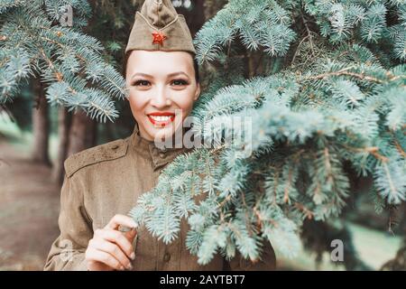 Una ragazza in una vecchia uniforme militare sovietica salutano in memoria parco. Vittoria della seconda guerra mondiale che celebra il 9 maggio in Russia Foto Stock