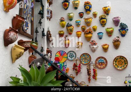 Ceramiche colorate appese su una parete di un negozio di souvenir in una strada stretta a Mijas, un piccolo villaggio sulla Costa del Sol vicino a Malaga in Andalusia, Spa Foto Stock