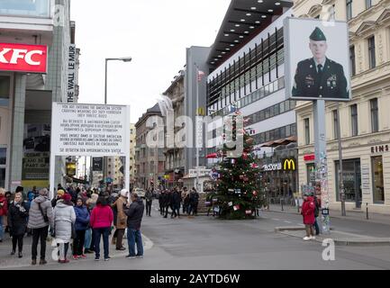 Berlino, Germania - 20 dicembre 2019: la gente visita famoso Checkpoint Charlie a Berlino. Durante la Guerra fredda era il più noto che attraversa Berlino Wa Foto Stock