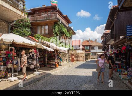 Nessebar, BULGARIA - 26 GIUGNO 2019: Negozi di souvenir sulla strada della città turistica di Nessebar. I turisti anziani guardano i souvenir Foto Stock