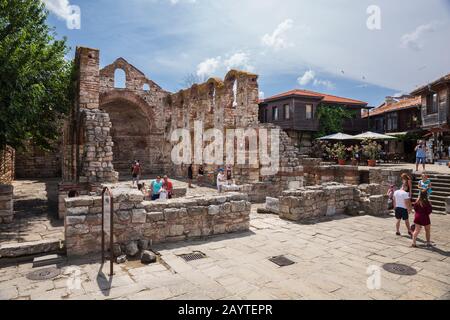 Nessebar, BULGARIA - 26 GIUGNO 2019: I turisti scattano foto e scattano selfie sullo sfondo delle rovine dell'antica basilica di San Pietro Foto Stock