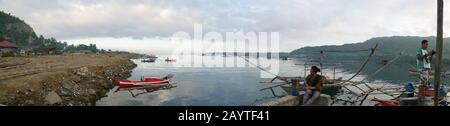 Banay Banay, Davao Oriental, Filippine - marzo 2016: Colpo panoramico di un villaggio di pescatori con persone in barca al molo. Foto Stock