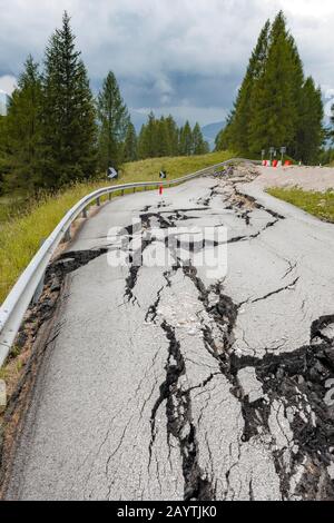 Strada danneggiata, strada rotta con crepe nel fondo stradale, carreggiata rotta di una strada di montagna, Belluno, Italia Foto Stock