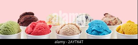 Grande assortimento di gelati artigianali italiani in una gamma di colori e sapori serviti in vasche da asporto su sfondo rosa Foto Stock