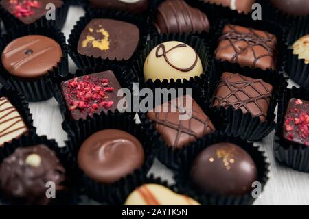 Collezione di caramelle al cioccolato in diverse forme e gusto ricoperto di carta nera con volant. Concetto di antiossidante gustoso, primo piano. Foto Stock