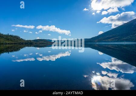 Bellissimo paesaggio di montagna riflessione gamma in acqua. Vista sulle montagne con superficie liscia a specchio del lago. Parco Delle Montagne Di Craddle In Tasmania, Foto Stock