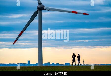 Walker sul mucchio di scorie di Hoheward a Herten, centrale eolica sul mucchio di scorie di Hoppenbruch, vista dello skyline di Essen, NRW, Germania Foto Stock