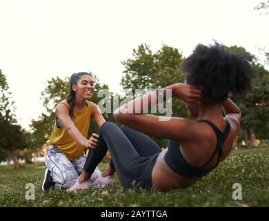 Giovani amici femminili sportivi che si adattano attivamente si siede sull'erba verde nel parco Foto Stock