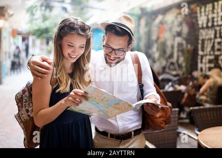 Vacanze, amore, la datazione e il concetto di turismo - Coppia sorridente con mappa della città Foto Stock