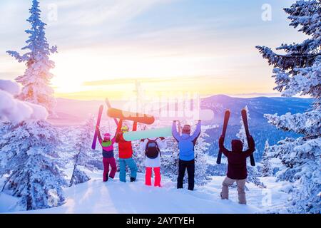 Squadra felice di snowboarder e sciatore che si divertono a sgombrare la neve. Sole leggero nella foresta invernale alba Foto Stock