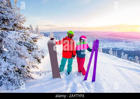Due amici attivi snowboarder e sciatore in piedi sulla cima della montagna cielo blu alba. Concept stazione sciistica foresta invernale Foto Stock