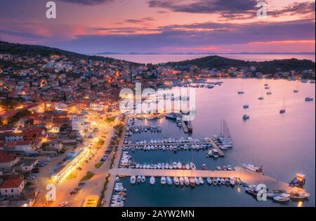 Vista aerea di barche e yacht in porto e città di notte. Foto Stock