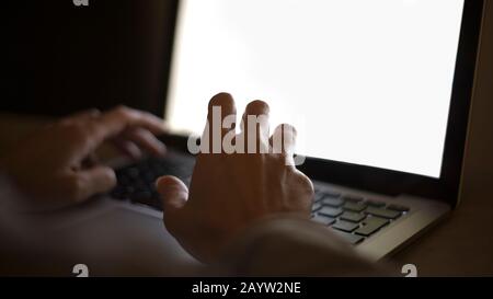 Relazioni di coppia e datazione nel concetto moderno di tempi: Primo piano delle mani della donna digitando sulla tastiera del laptop con lo schermo bianco in luce bassa Foto Stock