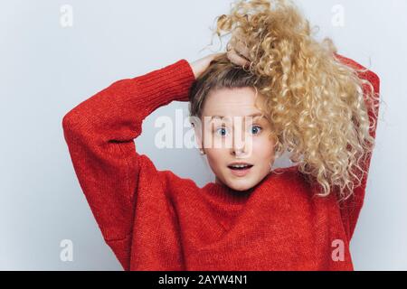 Impressionabile sorpresa femminile straes alla macchina fotografica con sguardo inatteso, mantiene i capelli nella coda del pony, esprime il sursursursment, isolato sopra il backgrou bianco dello studio Foto Stock