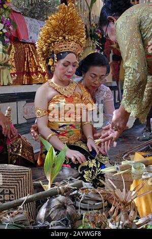 Una sposa Balinese e' guidata attraverso una tradizionale cerimonia da altre donne Balinesi. Foto Stock