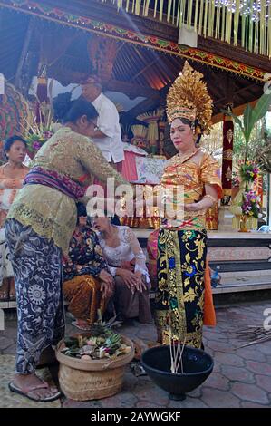 Una sposa Balinese e' guidata attraverso una tradizionale cerimonia da altre donne Balinesi. Foto Stock