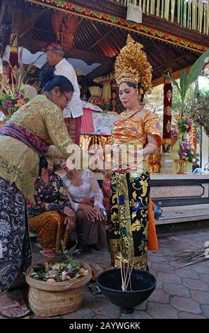 Una sposa Balinese e' guidata attraverso una tradizionale cerimonia da altre donne Balinesi. Foto Stock