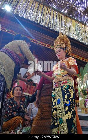 Una sposa Balinese e' guidata attraverso una tradizionale cerimonia da altre donne Balinesi. Foto Stock