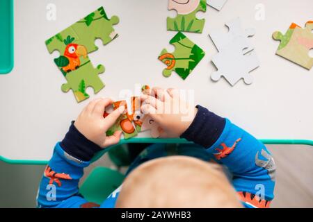 Bambino ragazzo risolvere puzzle puzzle puzzle sulla scrivania, concentrandosi sulle mani Foto Stock