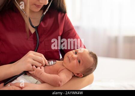 Esami pediatrici di giovane medico neonato con stetoscopio in ospedale Foto Stock