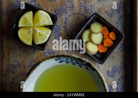 Zenzero, limone e tè curcuma con i suoi ingredienti su una tavola di legno Foto Stock