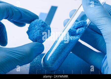 I ricercatori mostrano il materiale cristallino blu nella provetta manuale e in vetro in laboratorio Foto Stock