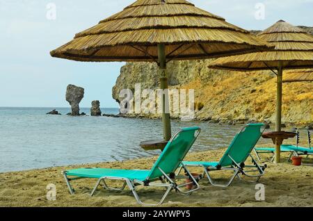 Grecia, formazione di roccia e sedie da spiaggia ad Agios Ioannis sull'Isola di Lemnos Foto Stock