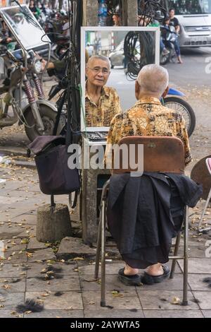 Vietnam Hanoi barbiere - un barbiere all'aperto in attesa di clienti sulla strada di Hanoi, Vietnam, Sud-est asiatico. Foto Stock