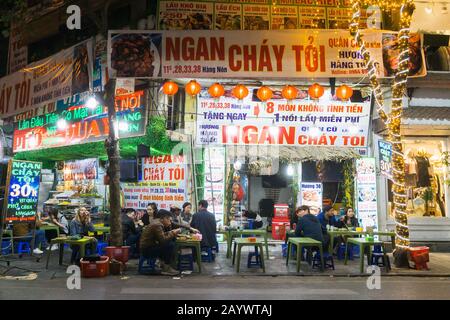 Hanoi Street food - persone che hanno cena su sgabelli di plastica nel vecchio quartiere di Hanoi, Vietnam, Sud-est asiatico. Foto Stock