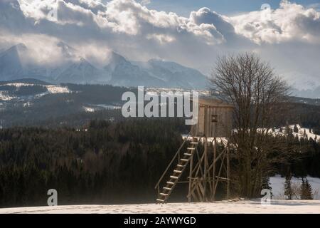 Torre di caccia su campo nevoso in montagna d'inverno Foto Stock