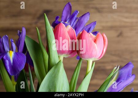 Tulipani rossi e iridi su sfondo di legno marrone. Buon compleanno di sfondo. Carta del giorno della madre. Congratulazioni per la giornata delle donne. 8 Marzo sfondo. Molla Foto Stock