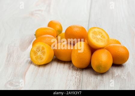 Mucchio di frutti di kumquat, mandarini cinesi, su tavola di legno. Foto Stock