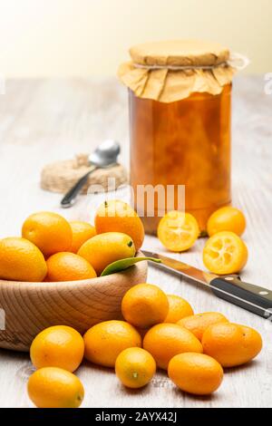 Mucchio di frutta di kumquat, tangerini cinesi, su tavola di legno con jar di marmellata. Foto Stock