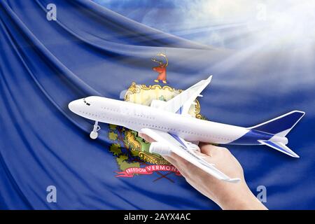 Aereo in mano con bandiera nazionale Stato del Vermont su uno sfondo di cielo blu con raggi di sole Foto Stock