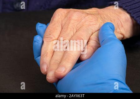 Il caregiver tenendo i pazienti anziani mano a casa Foto Stock